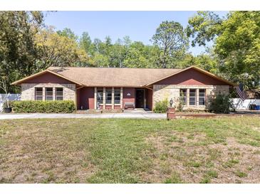 Charming single-story home features a brick facade, manicured lawn and mature trees at 10134 Buck Dr, New Port Richey, FL 34654
