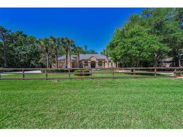 A spacious, sprawling lawn leads up to a beautiful home with a gated drive in a serene setting at 10808 Alico Pass, New Port Richey, FL 34655