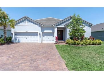 Welcoming single-story home with a brick driveway, three-car garage, and professionally landscaped front yard at 12617 Wetmore Ct, Odessa, FL 33556