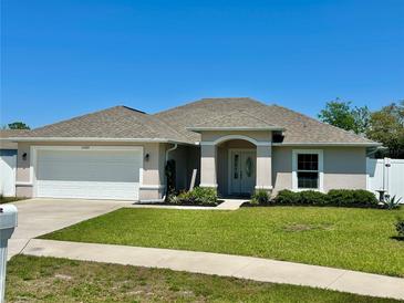 Charming single-story home with well-manicured lawn, neutral paint, and attached two car garage at 15585 Rene Ct, Brooksville, FL 34604
