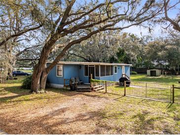 Charming home with a large tree in the front yard and a grill, presenting a welcoming curb appeal at 1916 & 1910 Beachway Ln, Odessa, FL 33556
