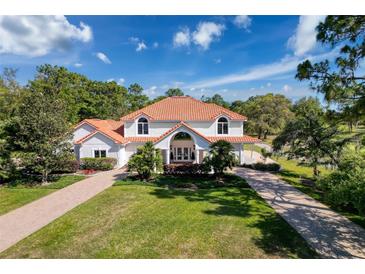 Beautiful white home features manicured lawn, two story construction and tile roof at 5198 Legend Hills Ln, Brooksville, FL 34609