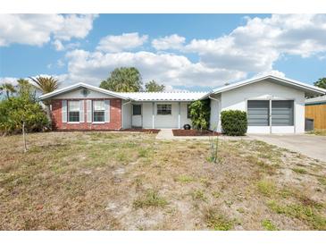 Inviting single-Gathering home with an attached garage, complemented by a neatly kept yard and clear blue skies at 10309 Honeysuckle Ln, Port Richey, FL 34668
