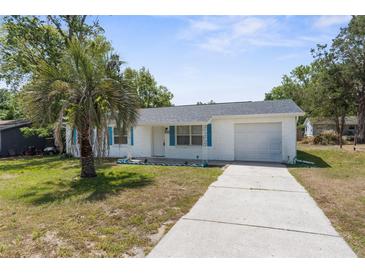 Charming single Gathering home boasts a freshly painted exterior, single car garage and tropical landscaping at 27198 Simona Ave, Brooksville, FL 34602