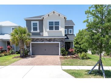 Inviting two-story home featuring a brick driveway, stone accents, gray painted facade, and well-manicured landscaping at 2815 Dudley Ave, Odessa, FL 33556