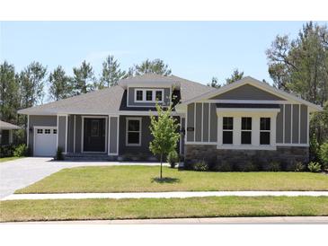 Charming single-story home featuring a manicured lawn, stone accents, and a welcoming front entrance at 6063 Dusk Rose Ln, Brooksville, FL 34601