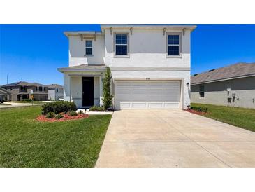 Two-story home with a large driveway and a two-car garage, along with manicured landscaping at 6561 Seaway Dr, Brooksville, FL 34604
