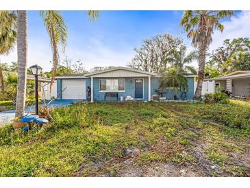 Charming single-story home with blue exterior, front yard, palm trees and one-car garage at 6614 Manor Beach Rd, New Port Richey, FL 34652