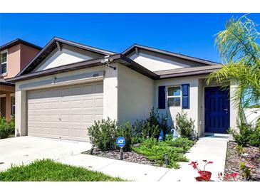 Charming single-Gathering home featuring a two-car garage, manicured landscaping, and a vibrant blue front door at 680 Argyll Dr, Spring Hill, FL 34609