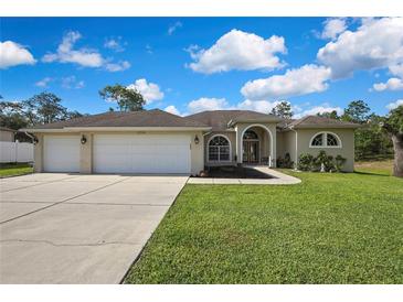 Charming single-story home with a three-car garage, arched entryway, and well-maintained lawn at 11336 Flower Ave, Weeki Wachee, FL 34613