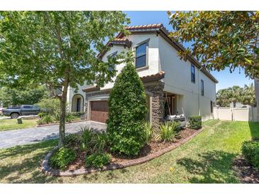 Two-story home features a front yard with lush landscaping, a paver driveway, and a cozy porch swing at 12889 Burns Dr, Odessa, FL 33556