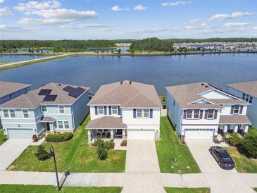 Beautiful aerial view of homes near a lake, featuring manicured lawns and scenic water views on a sunny day at 3208 Living Coral Dr, Odessa, FL 33556