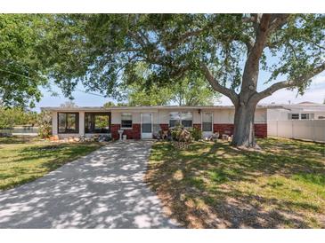 Charming single-story home with a brick facade, screened in porch, and a spacious front yard with mature trees at 6521 Boatyard Dr, Hudson, FL 34667