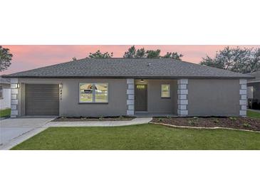 Charming single-story home featuring a well-manicured lawn, gray stucco, and an attached garage at 8413 Monarch Dr, Port Richey, FL 34668