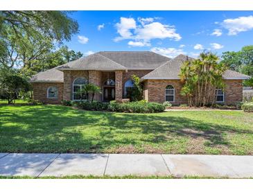 Charming brick home featuring manicured lawn and mature trees, perfect for curb appeal at 888 Royal Birkdale Dr, Tarpon Springs, FL 34688