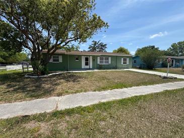 Charming green home featuring a well-manicured front yard with mature tree and sidewalk at 9285 Carthage Rd, Spring Hill, FL 34608