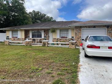 Charming single Gathering house featuring a stone facade, lovely landscaping, and attached garage at 1127 Lodge Cir, Spring Hill, FL 34606