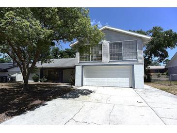 Two story home with an attached two car garage, mature trees, and a concrete driveway at 12210 Quail Run Row, Hudson, FL 34667