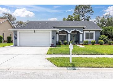 Charming single-story home featuring a well-manicured lawn and an attached two-car garage at 13524 Knotty Ln, Hudson, FL 34669