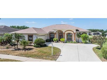 Charming single-story home featuring an arched entryway, lush landscaping, and a spacious driveway on a sunny day at 1420 Winding Willow Dr, Trinity, FL 34655