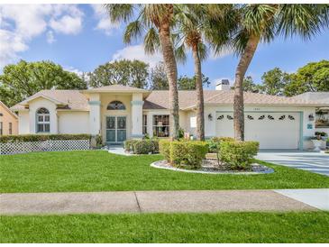 Charming single-story home with well-manicured lawn and lush landscaping at 1496 Overland Dr, Spring Hill, FL 34608