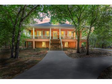 Charming two-story home featuring a wraparound porch, classic design, and lush, mature landscaping at 3431 Riderwood Dr, Dade City, FL 33523