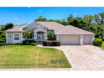 Stunning single-story home with a three-car garage, manicured lawn, and a welcoming front entrance at 3464 Misty View Dr, Spring Hill, FL 34609