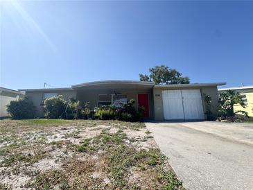 Charming single-story home featuring a red front door and attached garage on a sunny day at 5316 Drift Tide Dr, New Port Richey, FL 34652