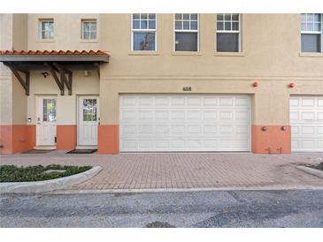 Tan two-story townhouse with a white garage door and nicely landscaped front at 658 Siren Wind Ln, Clearwater, FL 33756