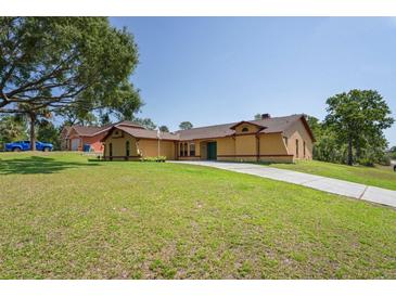 Charming home with lush lawn, long driveway, and inviting curb appeal under a clear blue sky at 7270 Nightwalker Rd, Weeki Wachee, FL 34613