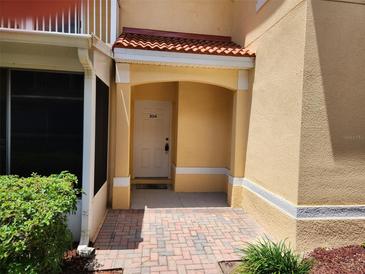 Charming condo entrance featuring brick pavers, and a covered porch with a red tile roof, offering a welcoming first impression at 21008 Sunpoint Way # 204, Lutz, FL 33558