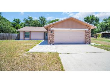 Charming single-Gathering home features a two-car garage with stone accents and a well-manicured front lawn at 2660 Orangewood Ct, Palm Harbor, FL 34684