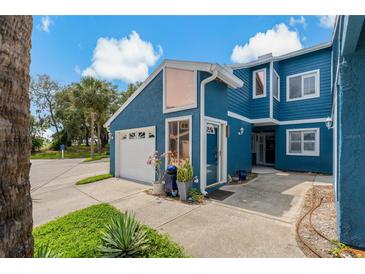 Charming two-story home with a blue exterior, front lawn, and attached one-car garage at 2026 Golfview Dr # 2026, Tarpon Springs, FL 34689