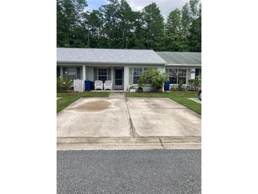 Charming townhome featuring a light gray roof, gray shutters, and a concrete parking pad at 2850 Westmoreland Ct, New Port Richey, FL 34655