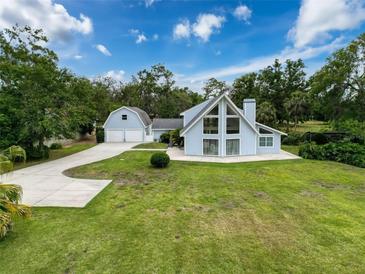 Inviting exterior with expansive lawn, two-car garage, and striking architectural details on a sunny day at 31726 Sylvian Ln, Dade City, FL 33525