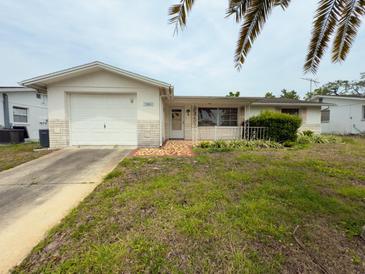 Charming single-story home featuring an attached garage, white exterior, and landscaping at 11224 Yewtree Ave, Port Richey, FL 34668