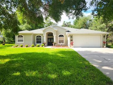 Charming single-story home featuring a manicured lawn, a two-car garage, and lush landscaping at 12270 Clarendon Ct, Spring Hill, FL 34609
