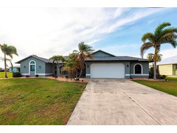 Charming single-story home with a well-manicured lawn and lush landscaping featuring palm trees at 305 Yellow Elder, Punta Gorda, FL 33955
