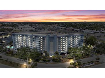 Condo building with waterfront access, swimming pool, and mature landscaping at dusk at 4939 Floramar Ter # 902, New Port Richey, FL 34652