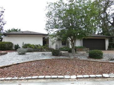 Charming single-story home with a manicured front yard featuring a tree, rock garden, and a two car garage at 7632 Lake Forest Cir, Port Richey, FL 34668
