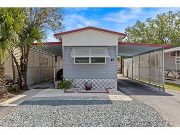 Charming gray home featuring a convenient carport and well-maintained landscaping at 800 Chesapeake Dr # 42, Tarpon Springs, FL 34689
