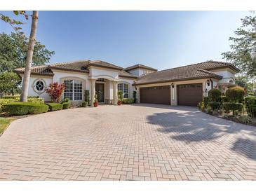 Stunning home showcasing an expansive brick driveway leading to a three-car garage and lush landscaping under a clear blue sky at 10645 Garda Dr, Trinity, FL 34655
