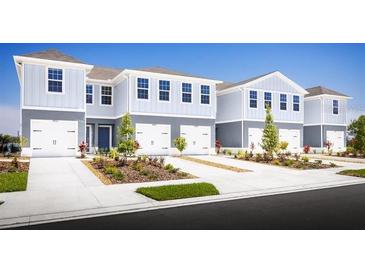 Charming light blue townhomes with well-manicured lawns on a clear, sunny day create an inviting curb appeal at 11410 Spectacled Dr, New Port Richey, FL 34654