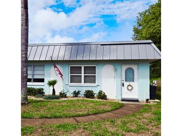 Charming single-story home with a well-manicured lawn, metal roof, and an inviting entryway with lovely shrubbery at 11631 Bayonet Ln, New Port Richey, FL 34654