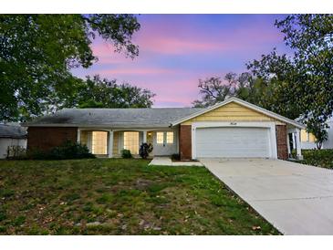 Charming single-story home with a well-manicured lawn, two-car garage and beautiful landscaping at sunset at 12411 Yorktown Ln, Hudson, FL 34667