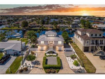 Stunning waterfront home with lush landscaping, brick driveway, and attached garages at sunset at 3352 Gulfview Dr, Hernando Beach, FL 34607