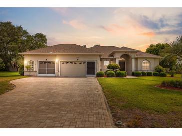 Charming single-story home featuring a well-manicured lawn, brick driveway, and three-car garage at 3400 Rosebay Ct, Spring Hill, FL 34609