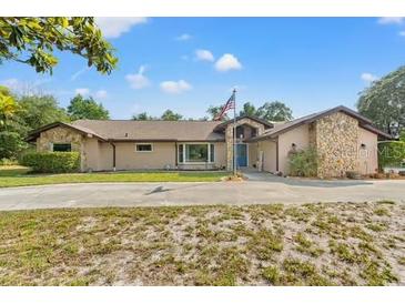Beautiful single-story home with stone accents, mature landscaping, and an American flag at 5216 Hope Ln, Spring Hill, FL 34606