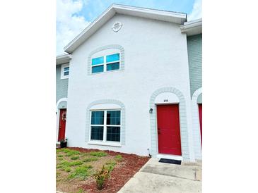 Two-story townhouse featuring a bright red front door and light gray trim at 5713 Townhouse Dr # 5713, New Port Richey, FL 34652