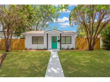 Charming single-story home with lush green lawn, modern teal door and mature trees at 5753 2Nd N Ave, St Petersburg, FL 33710